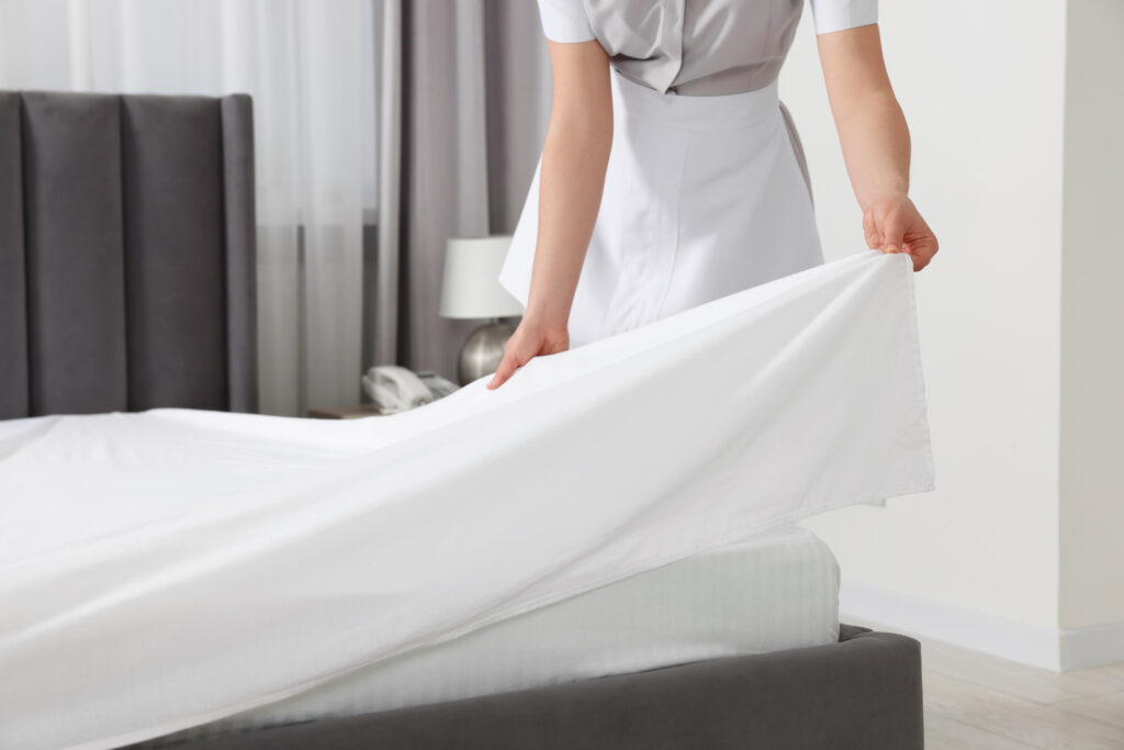 Maid making bed in hotel room, closeup